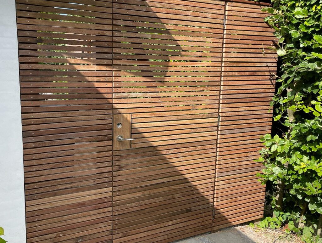 Moderne trælåge ved haveindgang i sollys